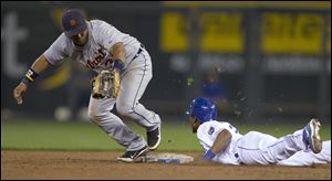 Kansas City Royals' Jarrod Dyson (1) dives back to the base during an attempted pick-off by Detroit Tigers second baseman Ramon Santiago (39) during the fifth inning.