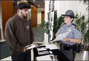 Eric Carros, Toledo, speaks with Trooper Teri Cavin of the Ohio State Highway Patrol, during a joint effort between Toledo police and the Highway Patrol to recruit potential new officers and troopers Tuesday at One Government Center.