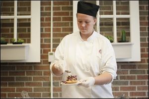 Second-year student Teri Easter makes a pork belly slider during a bacon-themed catered event Wednesday by the Culinary Arts students at Owens Community College.