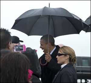 President Barack Obama greets people on the tarmac as he arrives on Air Force One in the rain at Cleveland Hopkins International Airport on Friday in Cleveland.