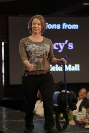 Amanda Holewinski on the runway with an assistance dog. She is modeling clothes from Macy's.