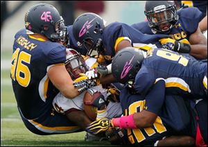 Central Michigan running back Anthony Garland is tackled by Toledo defenders, including  Hank Keighley, left, Robert Bell, bottom and Allen Covington, front right, Saturday at the Glass Bowl.