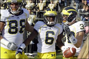 Michigan defensive back Raymon Taylor, center, celebrates with defensive end Craig Roh, left, and safety Jordan Kovacs after scoring a touchdown on a 63-yard interception.
