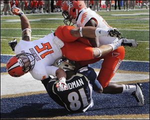 Bowling Green's Ryland Ward (15) and Aaron Foster tumble over Akron wide receiver Tyrell Goodman (81) after he caught a touchdown pass in the end zone Saturday.