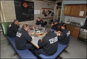 Firefighters from Station 6 eat lunch inside their small lunch room at the station on Starr Ave.