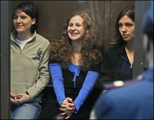Feminist punk group Pussy Riot members, from left, Yekaterina Samutsevich, Maria Alekhina, center, and Nadezhda Tolokonnikova sit in a glass cage at a court room in Moscow, Wednesday. The appeals court freed Samutsevich, but upheld a prison sentence for Tolokonnikova and Alekhina. 