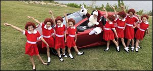 With several Annies on hand, Santa Claus poses with a 2013 McLaren 12C spider sports car Tuesday during the unveiling of the Neiman Marcus 2012 Christmas Book in Dallas.