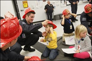 Penta student Tyler Rozek, 17, of Genoa, center left, helps Chase Cook, 4, of Perrysburg, put on his helmet during a fire safety training session Wednesday put on for the children by Penta's Public Safety/EMT-Fire Science program.