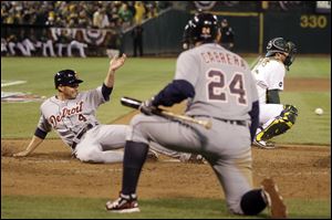 Tigers third baseman Miguel Cabrera watches as teammate Omar Infante scores at home.