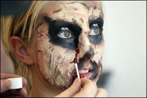 Carl Graf, a professional makeup artist, puts fake blood on Mary Beth Lengel to make her into a monster.
