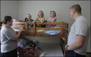 Hope, left, and Brandon Fritz, right, watch their three children -- Noah, 2, Makenzie, 6, and Bralynn, 3 -- sit on the bunk beds the girls received from First Presbyterian Church in Monroe. The church has a program to help families who cannot afford children's beds.