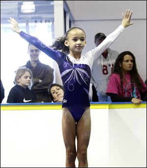 Halle Faulkner, 8, from Westland, Mich., ends her bar routine on the mat with a grin for the judges during a gymnastics meet..
