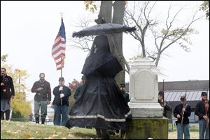 Dressed in period mourning attire, Kathy Dowd stands in Haughton Cemetery in light wind and rain with re-enactors during the Greater Toledo Civil War Roundtable’s annual cemetery walk.