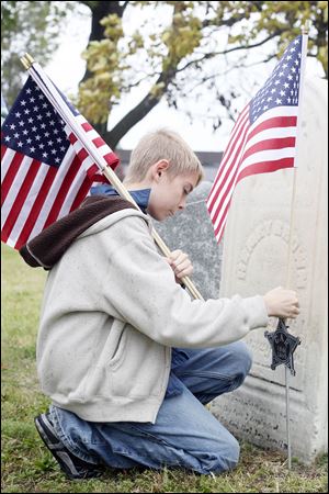 Maston Jaquillard, 11, a sixth grader at Navarre Elementary, puts flags on graves of Civil War Veterans during the annual cemetery walk. He said it was an 'honor to do it.'