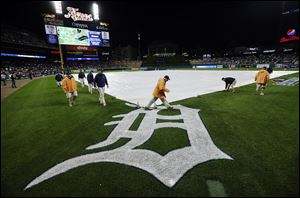Grounds crew members cover the field during a rain delay Wednesday during Game 4 of the American League championship series in Detroit.