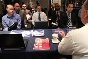 A group of veterans listen as a representative from White Rose Foods, foreground right, talks about their agency during a job fair introducing veterans to careers in the security and private investigations industry at Yankee Stadium in the Bronx borough of New York. 
