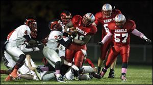 Bowsher's Mark Washington (30) eludes opposing would-be tacklers, including Rogers' Taylor McLane (23) on Thursday night in Toledo.