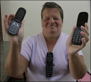 Betty Kasubski, of Maumee, who is blind, with the three phones she always wants with her, a cell, landline, and work phone.