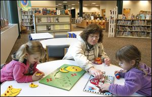 Gail Cifranic-Mills, center, helps her granddaughters Emaleth Cifranic, left, and Sophia Cifranic, right, with a puzzle at the Elyria Public Library on October 10, 2012.