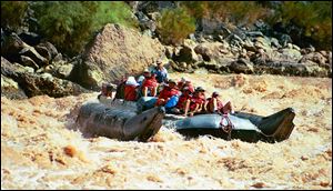 Visitors ride a pontoon raft through rapids in Grand Canyon National Park.