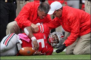 Ohio State Buckeyes quarterback Braxton Miller grimaces in pain as he is helped by trainers after getting injured in the third quarter.