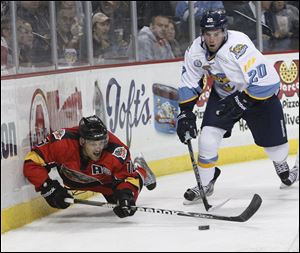 Phil Rauch, 20, knocks down Cincinnati Cyclones player Dan Eves, 16, as they battle behind the Walleye net.