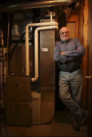 Allan Hoffman stands with his new, high efficiency furnace that will meet new federal standards coming next May, in the basement of his Coon Rapids, Minnesota home.