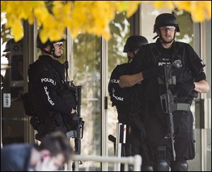 Police stand with guns drawn at the entrance to Brookfield Square Mall across from the scene of a shooting at Azana Salon in Brookfield, Wis. on Sunday.