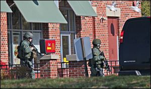 Tactical team members move past a McDonald's on the way to spa next door where, police say multiple people were wounded when someone opened fire, near the Brookfield Square Mall in Brookfield, Wis., Sunday.