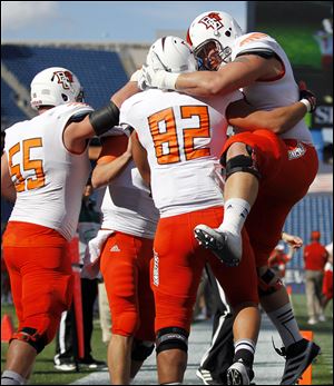 Bowling Green wide receiver Kevin Collins (82) celebrates his touchdown with teammates offensive linesman Alex Huettel (55) and offensive linesman Jordon Roussos, right, Saturday in Foxborough, Mass.