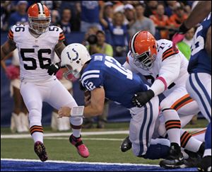Indianapolis Colts' Andrew Luck (12) goes in for a three-yard touchdown run against Cleveland Browns' Ahtyba Rubin (71) and Kaluka Maiava (56) during the first half of an NFL football game  Sunday.
