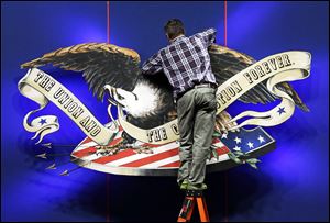 A worker adjusts the backdrop on stage in preparation for Monday's presidential debate between President Barack Obama and Republican presidential candidate, former Massachusetts Gov. Mitt Romney Sunday, at Lynn University in Boca Raton, Fla. 