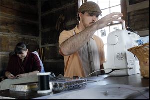 Angela Metcalf, left, and Robert Stewart, right, from Toledo, participate in a sewing circle at the Johlin Cabin at Pearson Metropark. Mr. Stewart has sewn for theater productions.