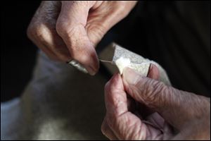 Ginny Giuetter of Oregon mends the seam of a historical dress while participating in a sewing circle at the Johlin Cabin at Pearson Metropark.