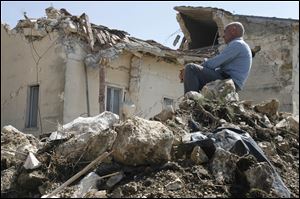 A man sits on rubble in the village of Onna, a day after a powerful earthquake struck the Abruzzo region in central Italy in April, 2009.