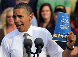 President Barack Obama holds up a copy of job plan during a joint campaign appearance with Vice President Joe Biden.