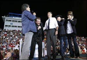 Republican presidential candidate and former Massachusetts Gov. Mitt Romney sings "God Bless America" as he campaigns at the football stadium at Defiance High School in Defiance, Ohio, with from left to right, Randy Owen, Meat Loaf, John Rich and Big Kenny.