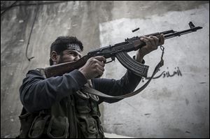A Free Syrian Army fighter shoots his gun towards government troops as rebel fighters belonging to the Liwa Al Tawhid group carry out a military operation at the Moaskar front line, one of the battlefields in Karmal Jabl neighborhood, in Aleppo, Syria. 