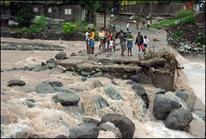 Residents stand on a bridge that was previously destroyed in 2008 by Tropical Storm Gustav, while watching Hope River swell in the village of Kintyre, near Kingston, Jamaica, after the passing of Hurricane Sandy on Thursday.