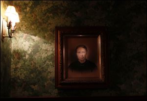 An old painting of an unidentified woman illuminated by a flashlight in the dining room of the Mansion View Inn in the Old West End.