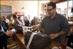 Co-owner  Dustin Hostetler stands at the till cashing out customers at Grumpy's.