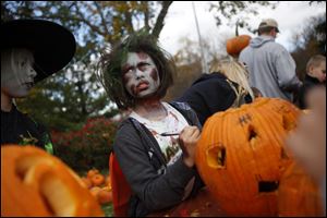 Jordan Hill, 9, dressed as a zombie, writes her name on her completed pumpkin.