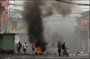 People walk past barricades set on fire by demonstrators during a protest in downtown Colon, Panama on Tuesday.