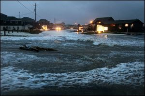 Ocean water rolls over state highway NC 12 in Buxton, N.C., on Hatteras Island at dawn as Hurricane Sandy works its way north, battering the East Coast. 