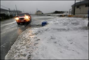 A truck backs up hastily, as rough surf of the Atlantic Ocean breaks over the beach and across Beach Avenue Monday in Cape May, N.J.