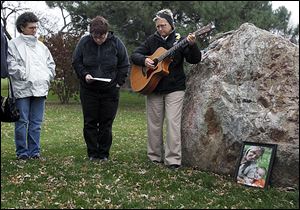 Gaby Davis, left, Michelle Clossick, and Lisa Binkowski gather around the Violence Against Women Memorial Rock at the Sanger Branch Library to share a moment of silence for Amber Jones, 26, of Lake Township and her son, Jorge Duran III, 3, shown in framed photo, along with Lorie Miller of Sandusky, who died this month in alleged acts of domestic violence.