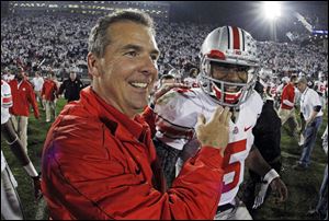 Ohio State head coach Urban Meyer, left, celebrates with Ohio State quarterback Braxton Miller (5) at the end of a 35-23 win over Penn State in an  NCAA college football game in State College, Pa.