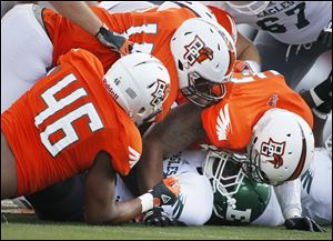 Bowling Green State University players Charlie Walker, 46, Gabe Martin, 11, and Paul Swan, 33, smother Eastern Michigan University player Bronson Hill, 30.