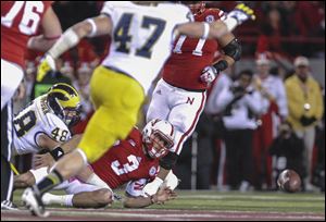 Nebraska quarterback Taylor Martinez fumbles the ball for a turnover after being tackled by Michigan's Desmond Morgan (48).