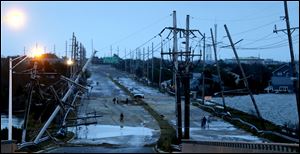 Downed power lines and a battered road is what superstorm Sandy left behind Tuesday as people walk off the flooded Seaside Heights island.
